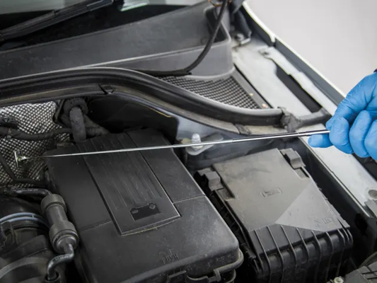 Person checking the oil level in a car engine with a dipstick.