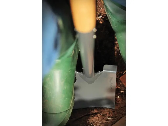 Close-up of a green garden tool with a blurred background