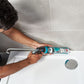 Person applying sealant to a bathroom wall with a caulking gun.