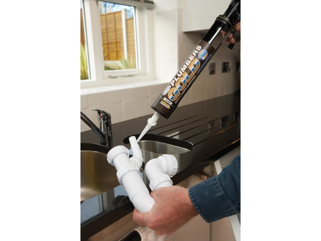 Person applying silicone sealant to a kitchen faucet