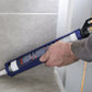 Person using a caulk gun to apply sealant along a bathroom wall.