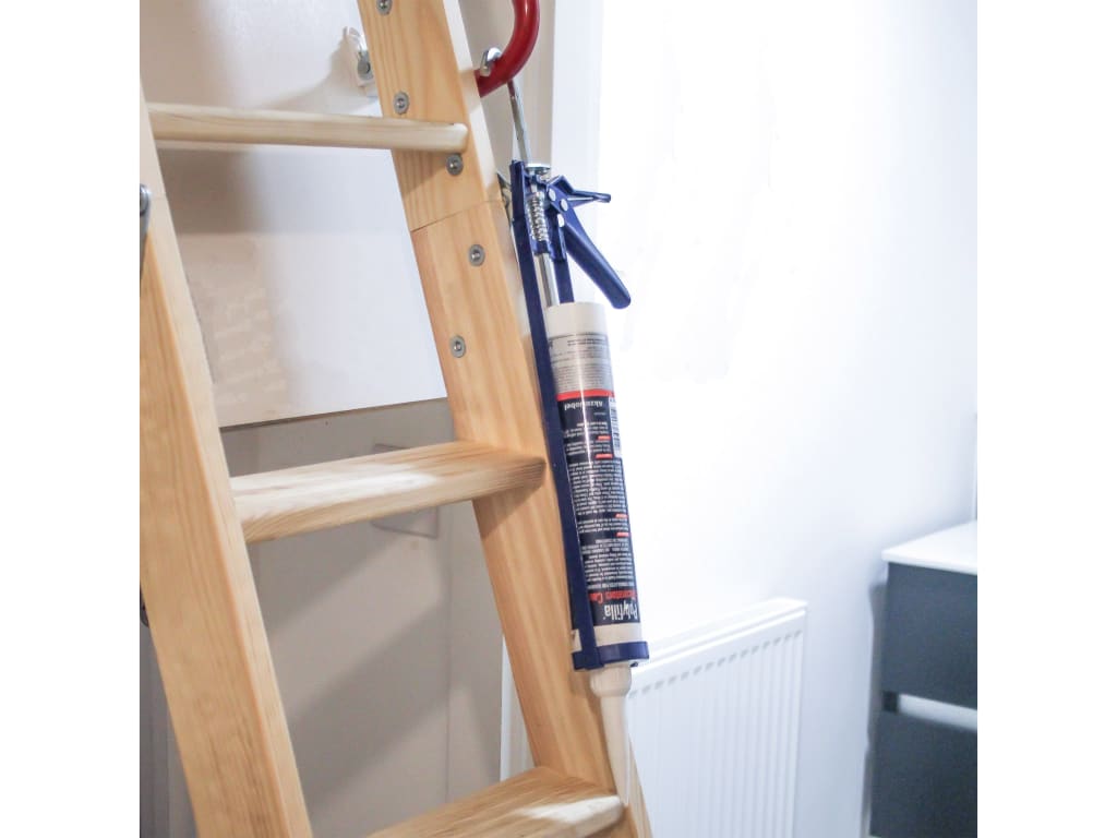 Wooden ladder with a caulking gun on a white background