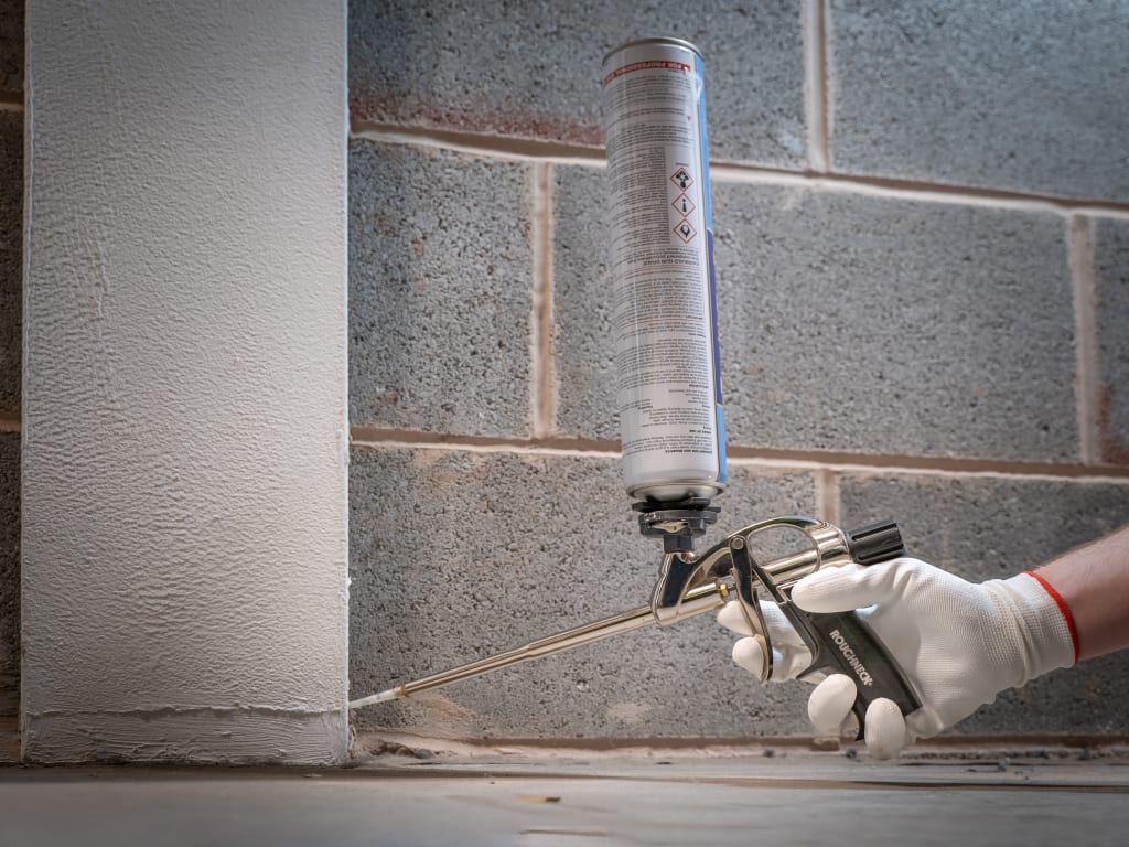 Person using a caulking gun on a brick wall