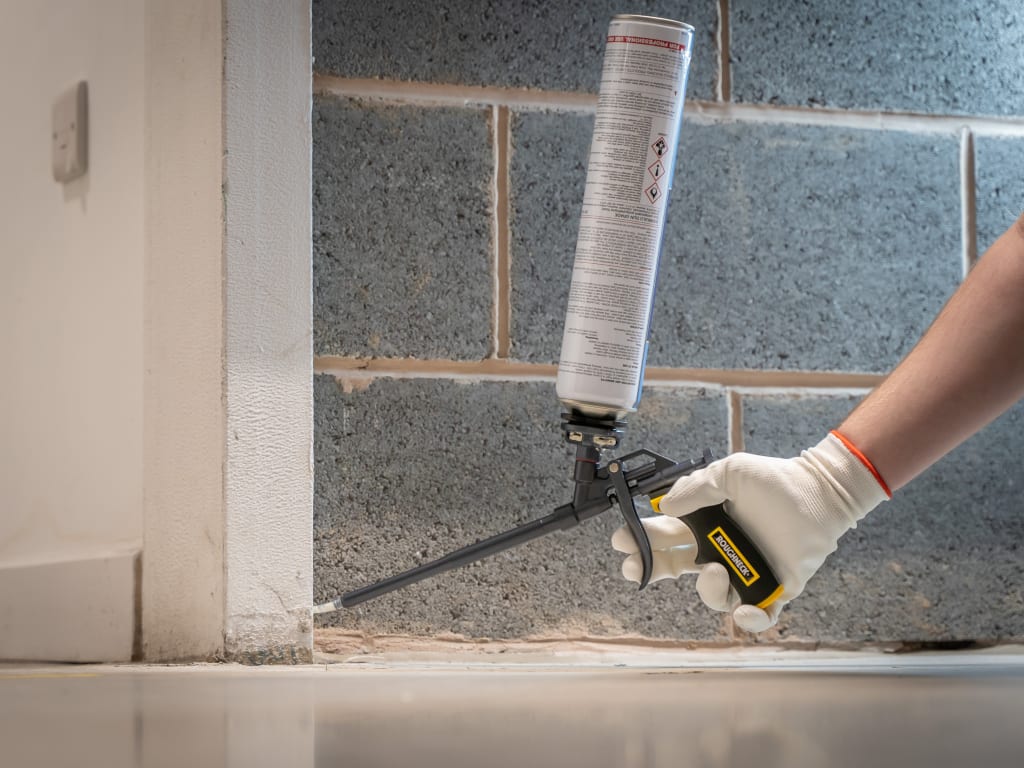 Person applying silicone sealant to a joint between tiles.