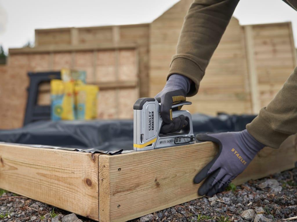 Person using a power tool on a wooden structure outdoors