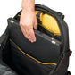 A close-up of a black laptop backpack with a person's hand inserting a closed silver laptop into the main compartment. The backpack features a bright yellow interior lining and yellow piping accents on the exterior.