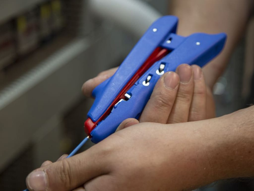 Close-up of hands using a blue tool with a red component.