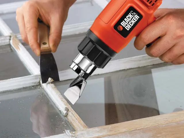 Person using a Black & Decker tool to work on a window frame.