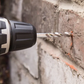 Drill bit being used to drill into a brick wall