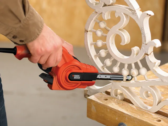 Person using a power tool on decorative metalwork