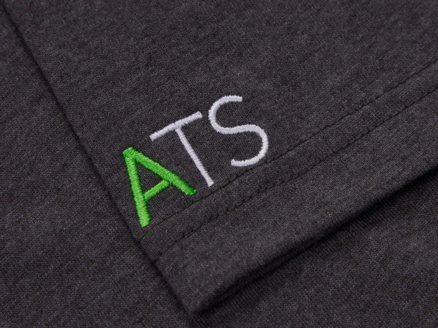 Embroidered 'ATS' logo on a dark fabric background