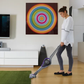 Woman using a stick vacuum cleaner in a modern living room.