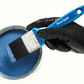Hand holding a BlueSpot paintbrush with a container of blue paint on a white background