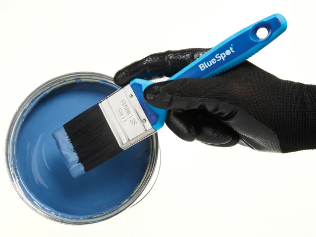 Hand holding a BlueSpot paintbrush with a container of blue paint on a white background