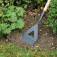 Gardening tool being used on garden soil with plants in the background