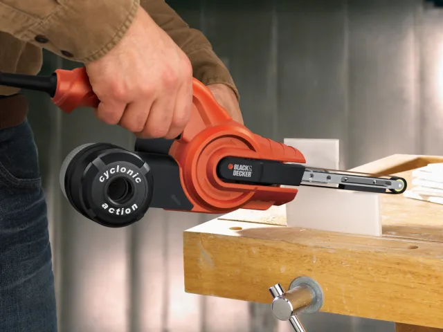 Person using a BLACK+DECKER power tool on a wooden surface