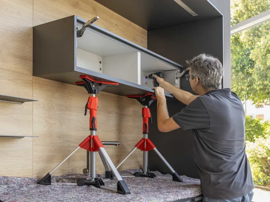 Person assembling a piece of furniture using a stand and tools.
