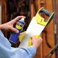 Person holding a saw and WD-40 spray can in a workshop setting
