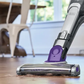 Vacuum cleaner cleaning a wooden floor in a room with furniture.