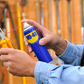 Person holding a can of WD-40 near pliers with a blurred tool chest background