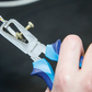 Close-up of a person using a blue and silver tool on a dark background