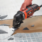 Person using a Black & Decker oscillating tool to cut tiles on a tiled floor.