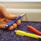 Hand holding a blue and silver pen next to other colorful pens on a textured surface.
