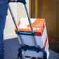 Person using a blue hand truck to move a box with Coca-Cola branding.
