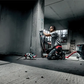Person using a power tool in an industrial setting with concrete walls and floor.