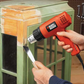 Person using a Black & Decker heat gun to work on a wooden surface.
