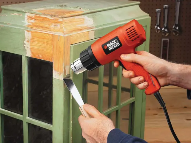 Person using a Black & Decker heat gun to work on a wooden surface.