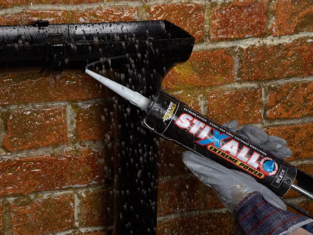 Person applying STIXALL Extreme Power sealant to a brick wall