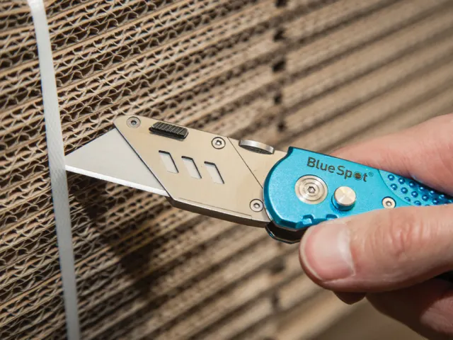 Person using a Blue Spot brand utility knife on cardboard