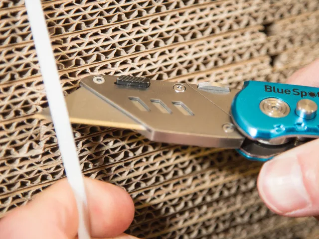 BlueSpa pocket knife being used to cut cardboard