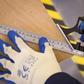 Person measuring wood with a ruler and wearing gloves