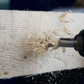 Woodworking tool shaving off wood shavings from a piece of wood.