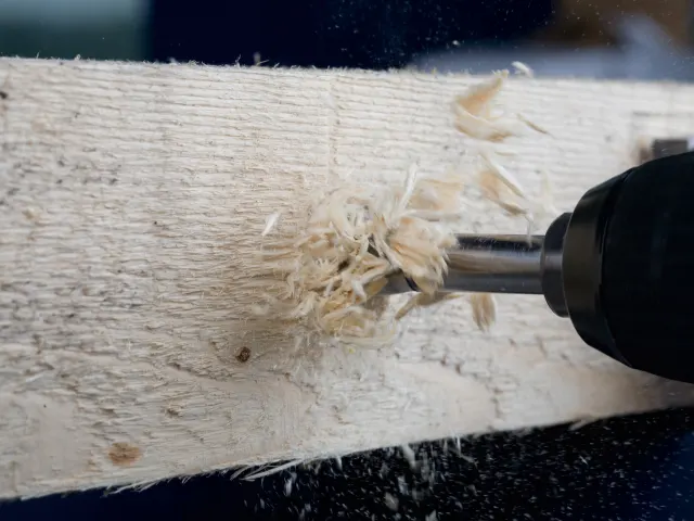 Woodworking tool shaving off wood shavings from a piece of wood.