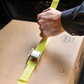 Person securing a cardboard box with a yellow strap inside a vehicle.