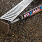 Stix All sealant gun applying sealant to a metal drain cover on a textured surface.