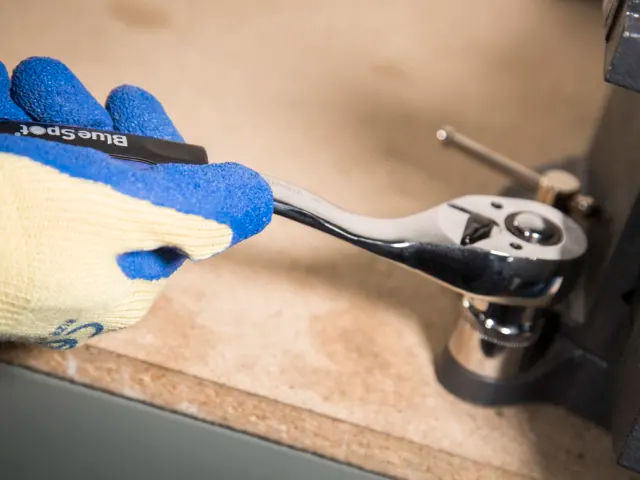 Hand using a wrench on a mechanical part with a blurred background