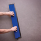 Person using a blue tool on a gray surface