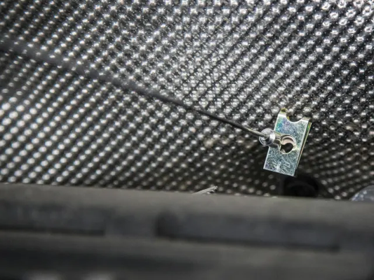 Close-up of a carbon fiber surface with a small metal component.