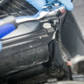 Close-up of a person using a tool on a mechanical component, wearing blue gloves.