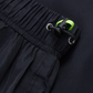 Close-up of black pants with a green tag on a dark background