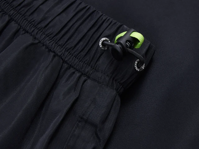 Close-up of black pants with a green tag on a dark background