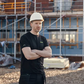 Man wearing a hard hat and black shirt standing on a construction site