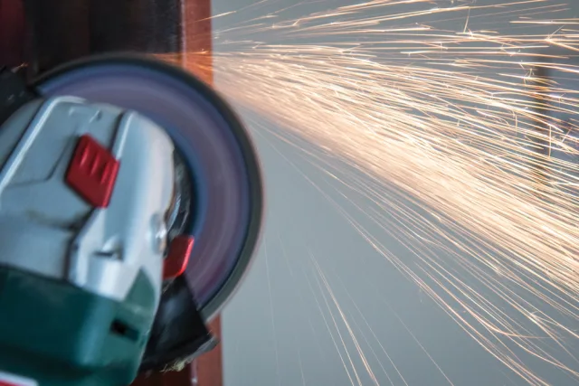 Close-up of a grinding wheel with sparks flying, indicating metalworking.