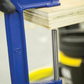 Blue vise holding a piece of wood on a workbench with a blurred background