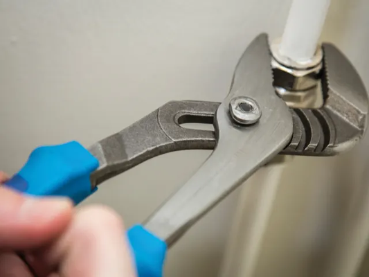 Plumbing wrench being used on a pipe with a neutral background