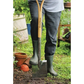 Person wearing green wellington boots holding a shovel in a garden setting